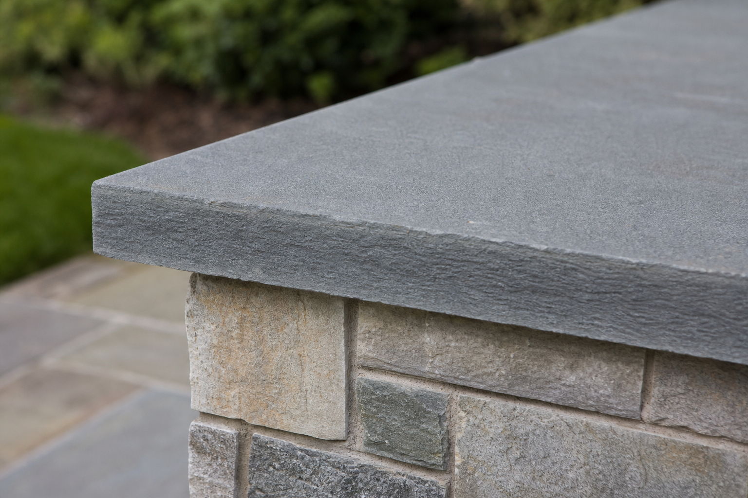 Bluestone cap on multi-tone stone veneer pillar showing masonry craftsmanship — representative design concept