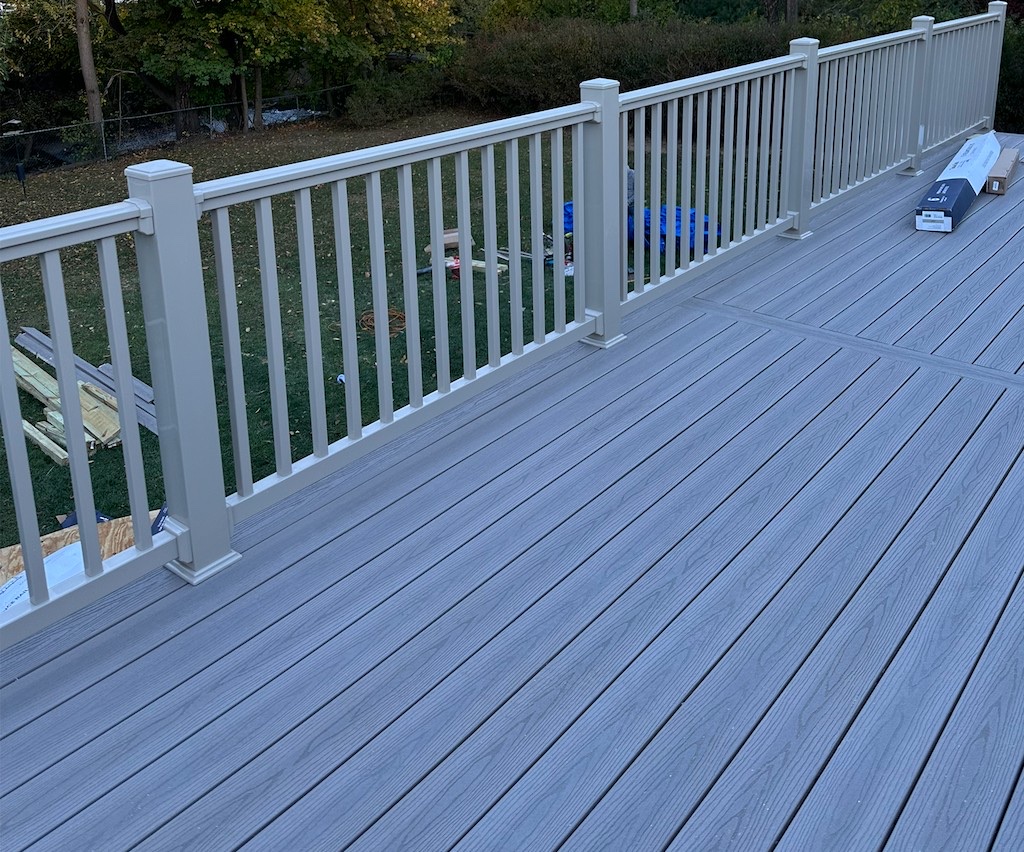 Corner view of a completed grey composite deck with taupe railing and picture-frame border in Northern New Jersey